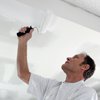 Painter with a rollerbrush painting ceiling white