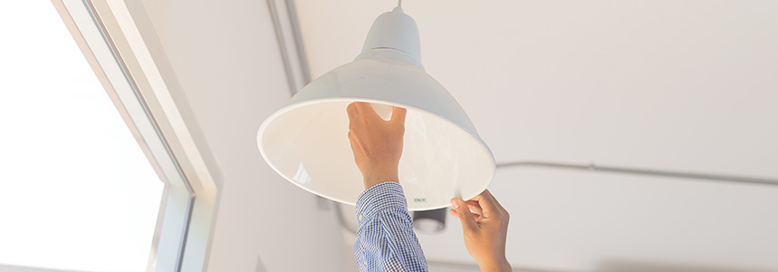Close up of a man changing a light fixture and putting in a new light bulb.