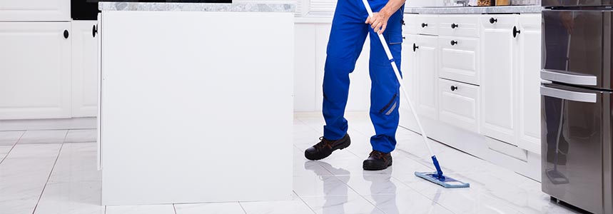 A man mopping the kitchen floor.